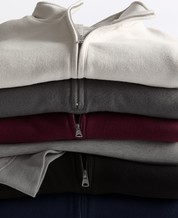 Stack of folded Women's Half-Zip Pullovers in cream, gray, burgundy, black, and navy.