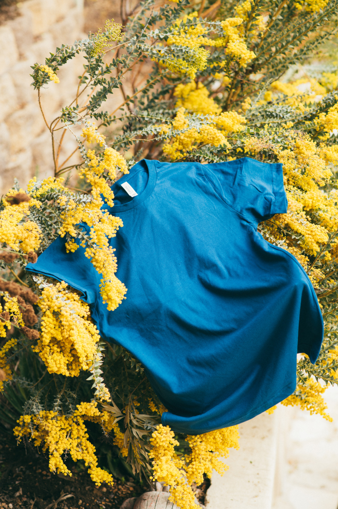blue t-shirt laying on yellow plants